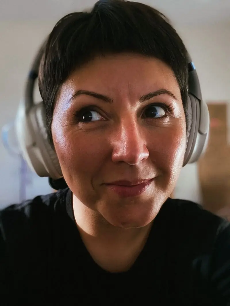 Ju Medeiros de fones de ouvido, olhando de lado com um sorriso